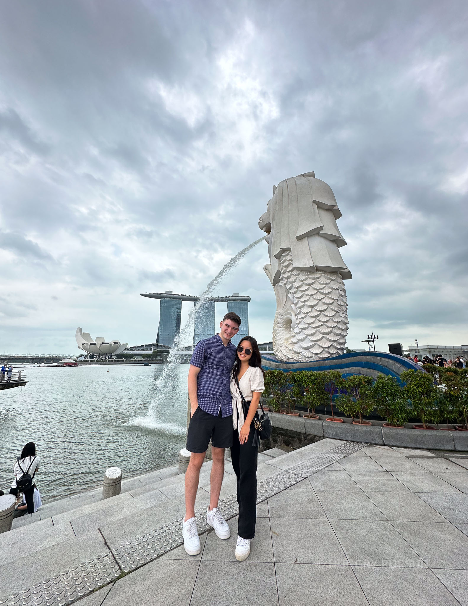 Couple striking a pose in front of the iconic Merlion statue, a famous landmark in Singapore
