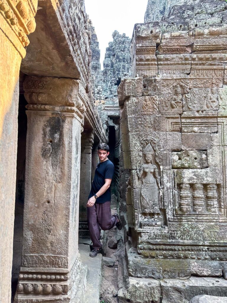 Man exploring Angkor Wat ruins, walking amidst ancient architecture in Cambodia