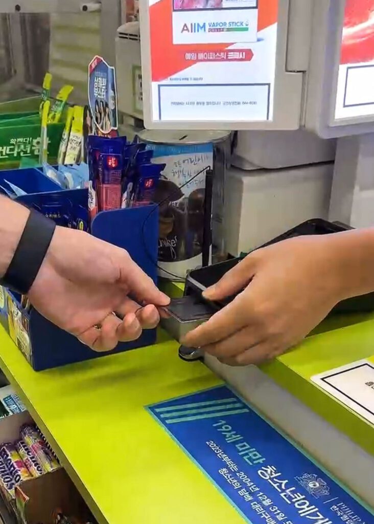 a man paying with a credit card at the korean conveniences store.