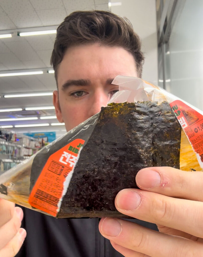 last stages of a man opening an onigiri at a korean convenience store.