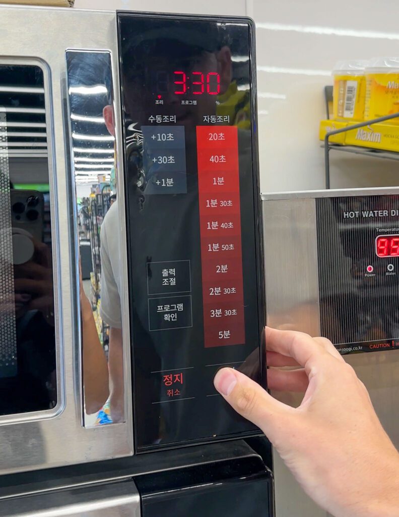 a hand pressing the microwave inside the Korean convenience store.