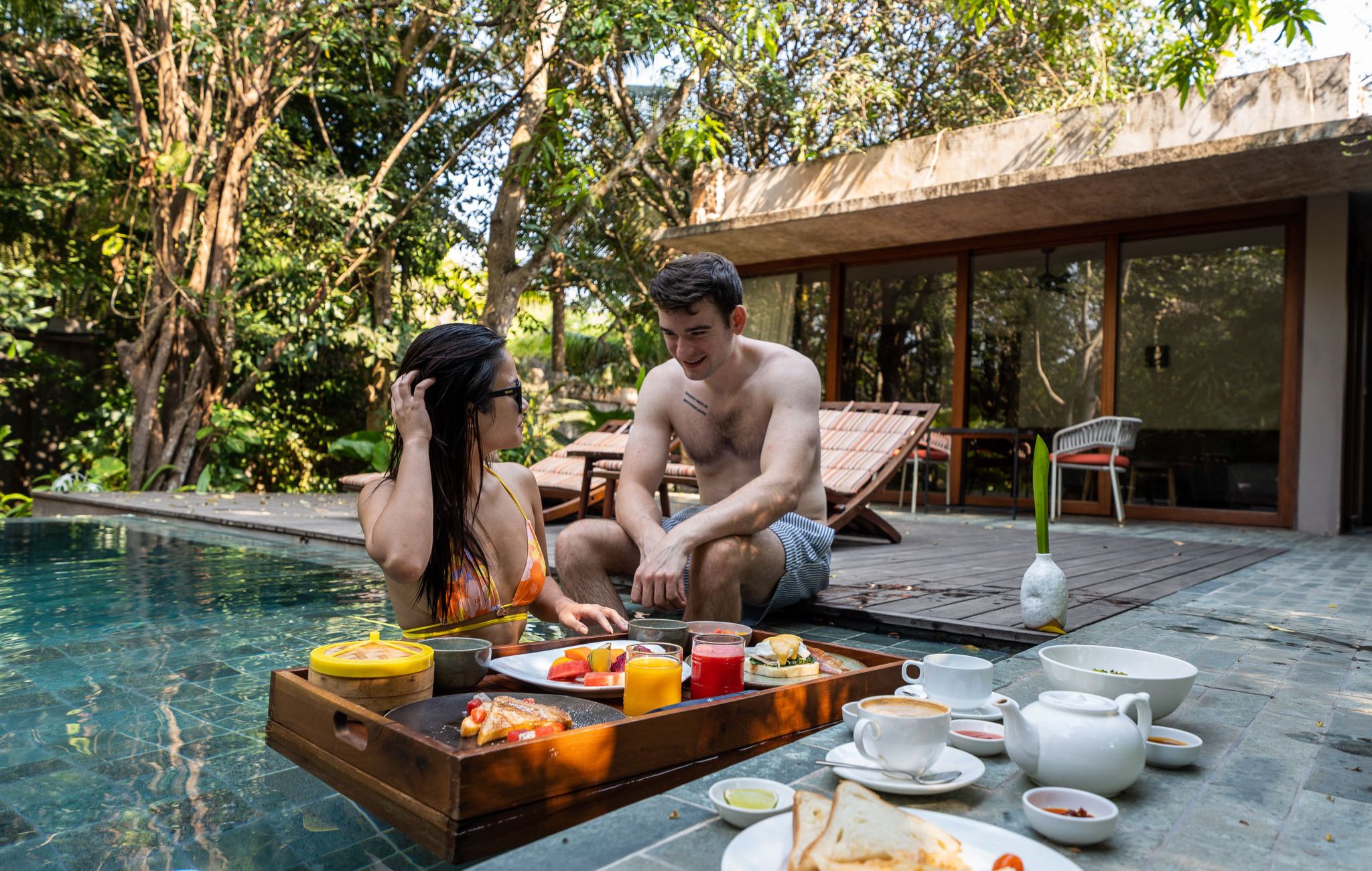 Couple enjoying a floating breakfast in the pool at Templation, a luxury hotel in Siem Reap, Cambodia.