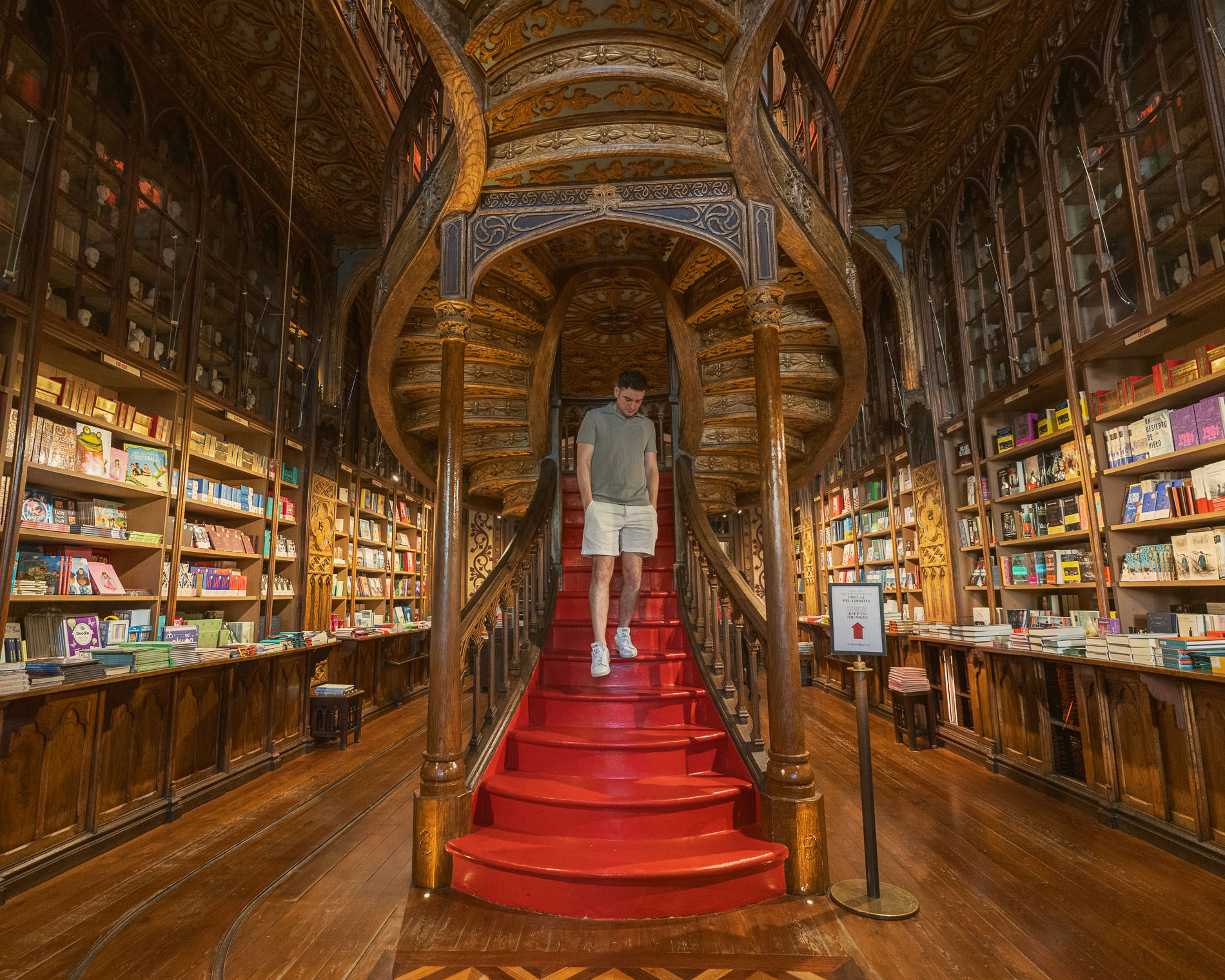 a man walking down the stairs in a bookstore, livraria lello; 1 day in porto