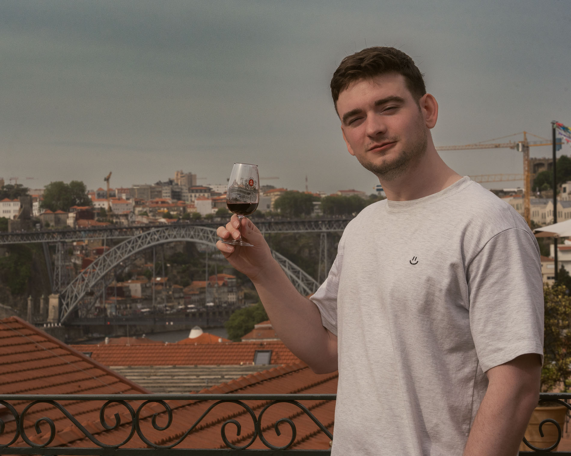 a man holding a glass of wine at the wine tasting with a view of a bridge in the background, 1 day in Porto