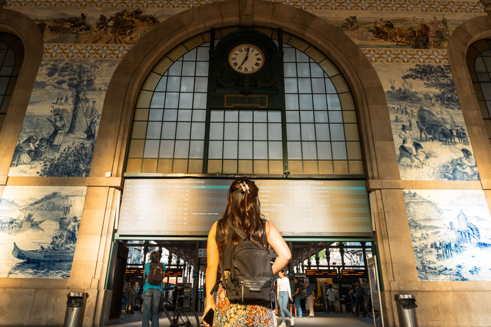 a woman observing the tile work in Sao bento train station, 1 day in Porto