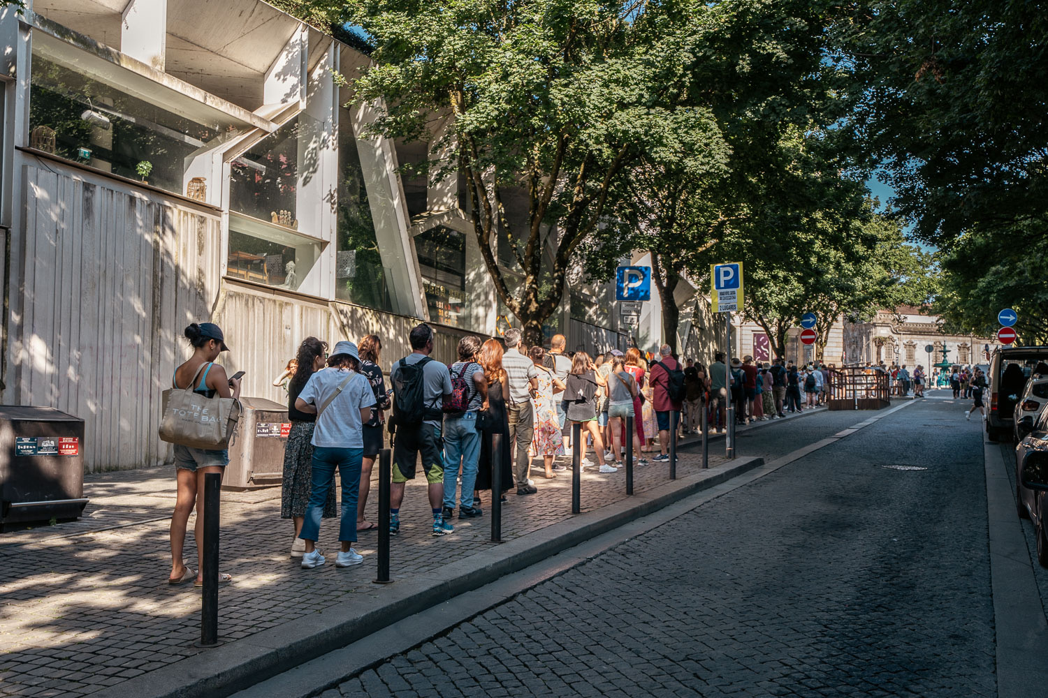 people waiting in line to enter a bookstore, livraria lello on this 1 day in Porto.