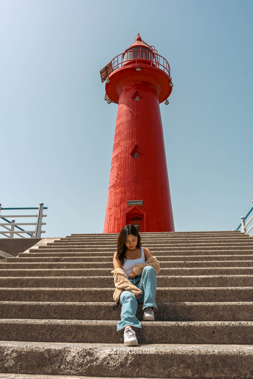 a woman posing looking down at Cheongsapo twin lighthouse at haeundae blueline park; things to do in busan