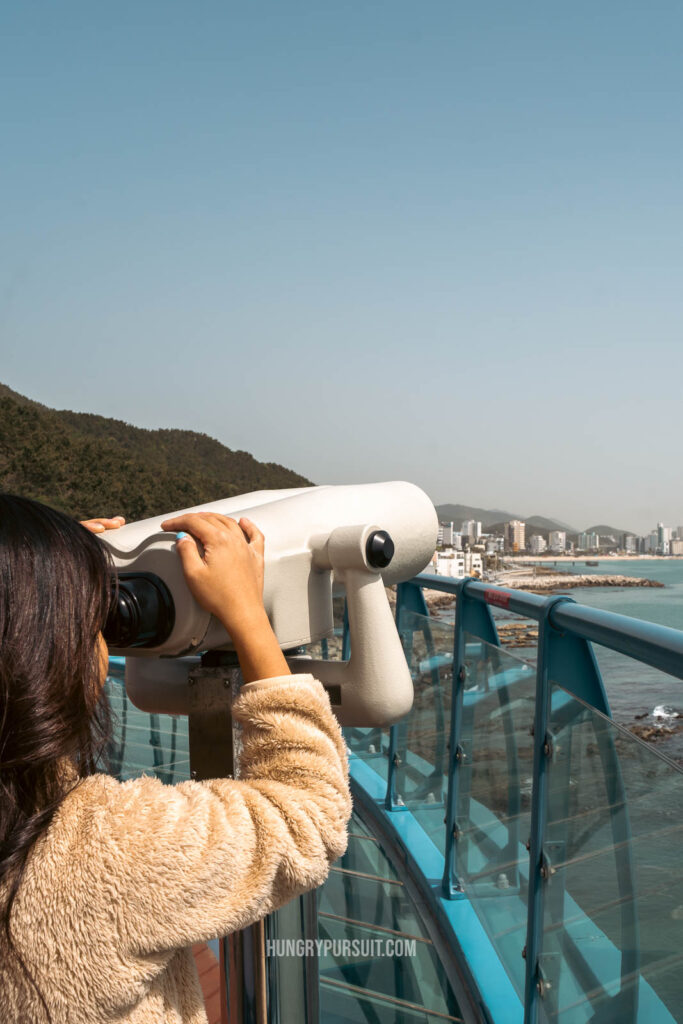 A woman using binoculars at Cheongsapo doritdol observatory; haeundae blueline park photos