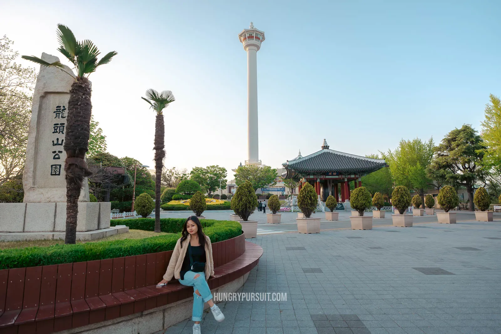 a woman sitting in front of the busan tower; things to do in busan.