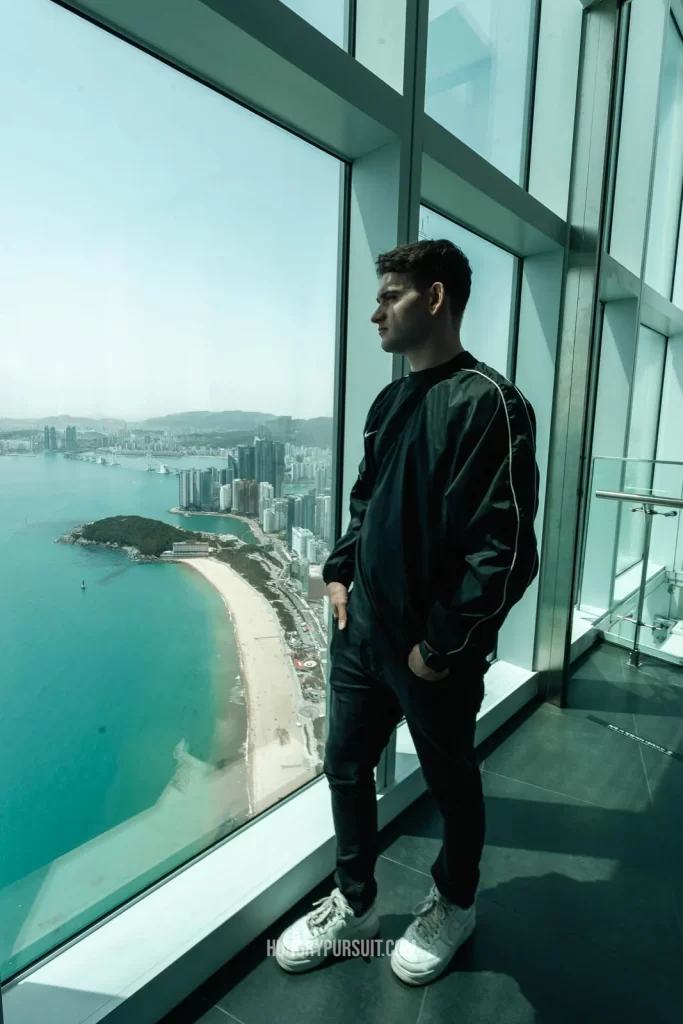 a man standing looking out the 100th floor observatory of Busan X The Sky