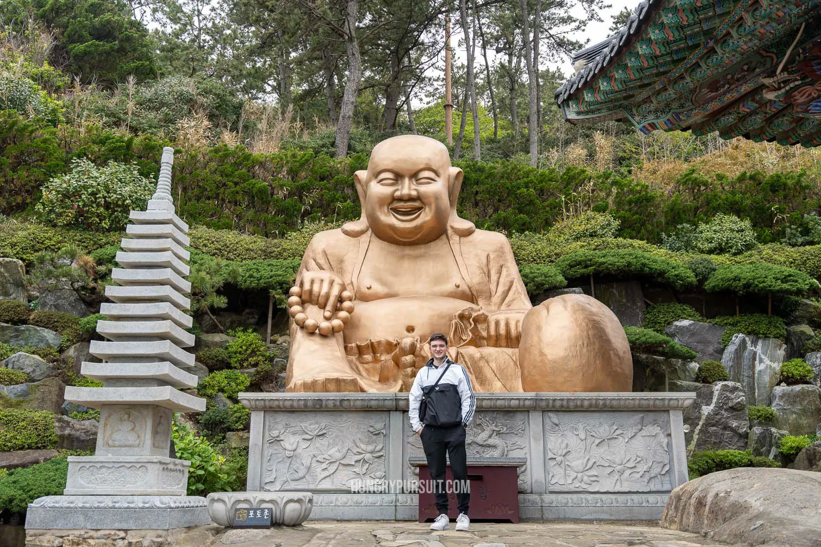 a man standing in front of budha statue at Haedong Yongggunsa temple; things to do in busan