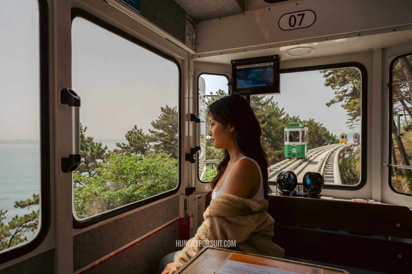 a woman inside Haeundae sky capsule at haeundae blueline park; things to do in busan