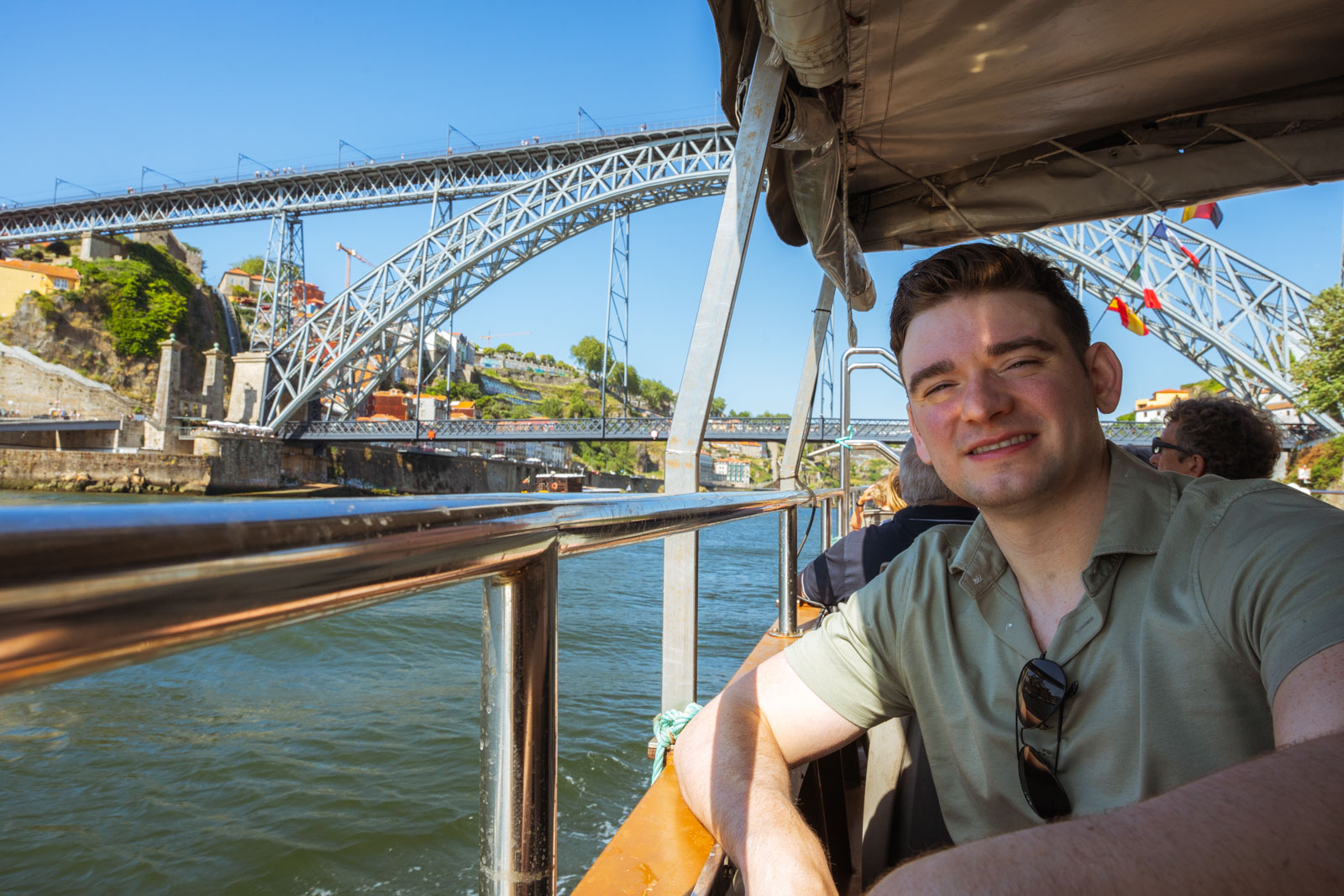 a man seated on duoro river cruise with Dom Luis Bridge in the background; 2 days in porto itinerary.