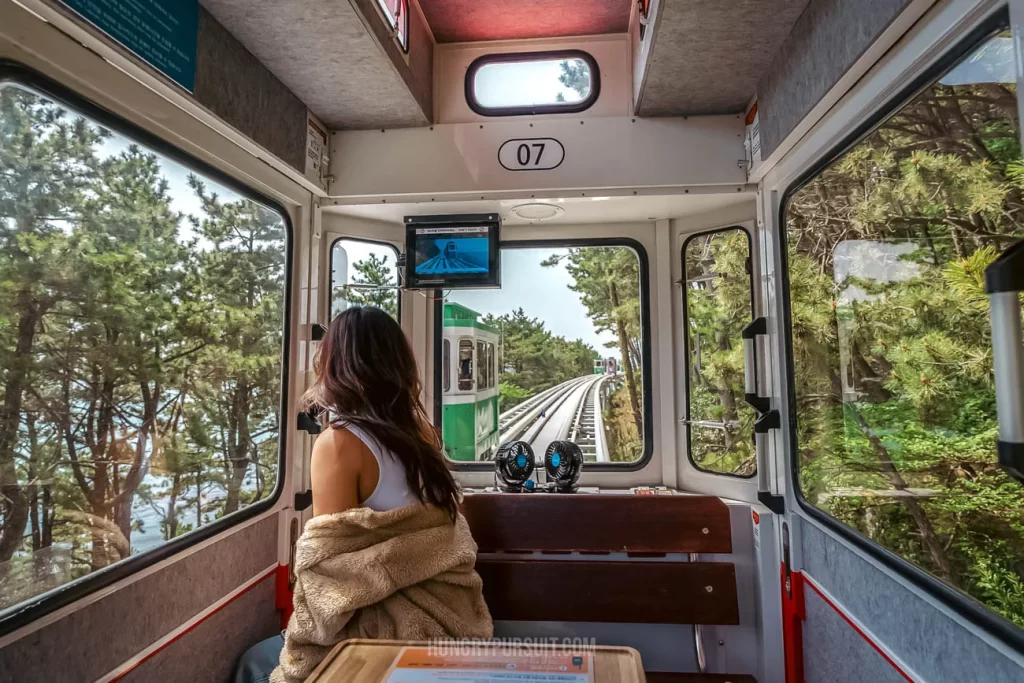 a woman inside Haeundae sky capsule at haeundae blueline park; things to do in busan