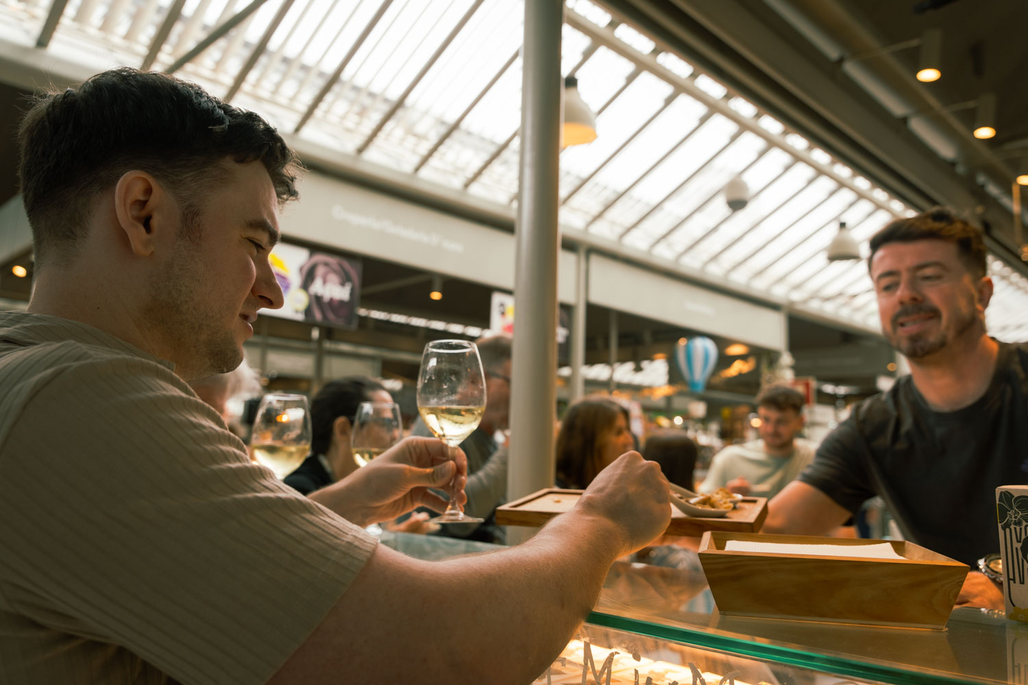 a man holding a glass of wine on food tour reaching for food; 2 days in Porto itinerary.