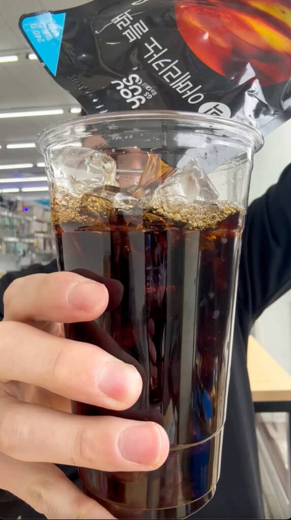 korean pouch drinks coffee man pouring into a plastic cup at a korean convenience store