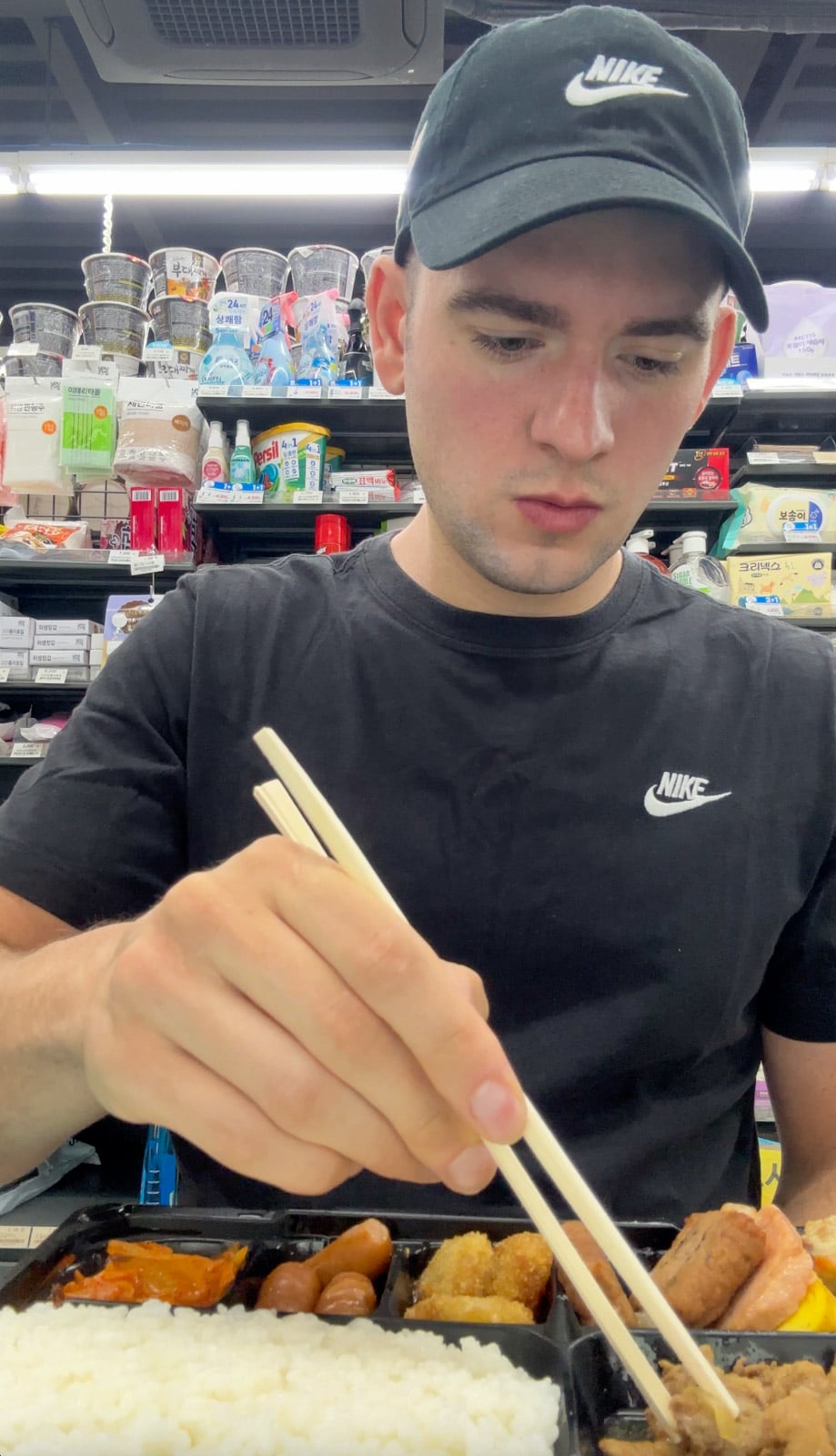 a man eating a pre-packaged korean convenience store food.